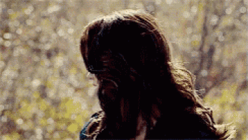 a woman with long hair is standing in front of a tree .