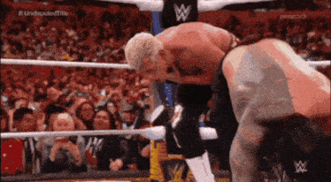two men are wrestling in a ring with a crowd watching and a peacock logo in the background