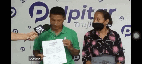 a man and a woman are standing next to each other in front of a microphone and holding a piece of paper .