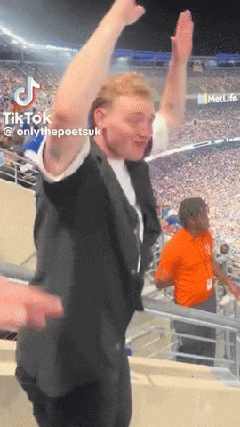 a man in a suit is dancing in a stadium with his arms in the air and a metlife logo in the background
