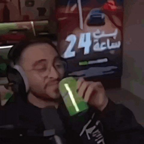 a man wearing headphones is drinking from a green cup .