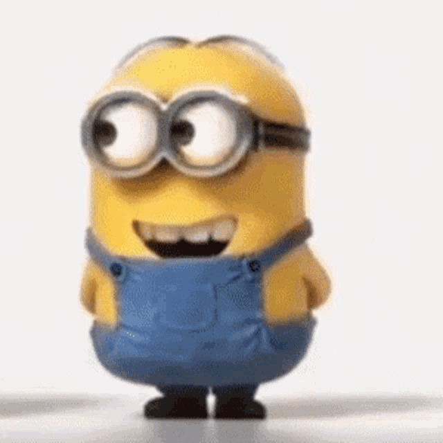 a cartoon minion wearing overalls and goggles is standing on a table .