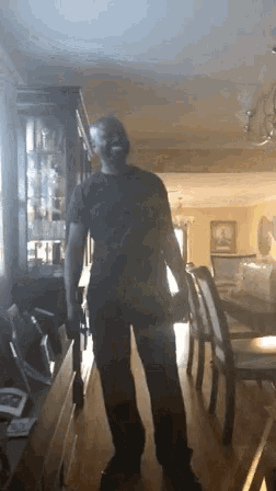 a man in a black shirt stands in a dining room
