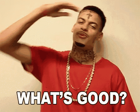 a man with a tattoo on his forehead is wearing a red shirt and gold chains .