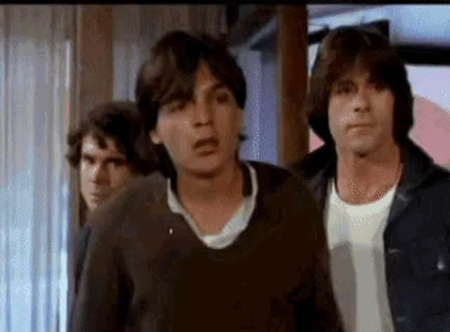 three young men are standing next to each other and one of them is making a face