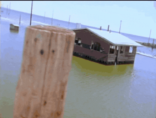 a wooden post stands in front of a flooded building