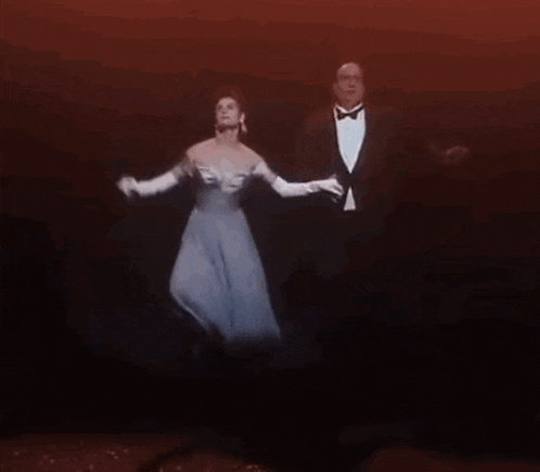 a man and a woman are dancing on a stage in a dark room .