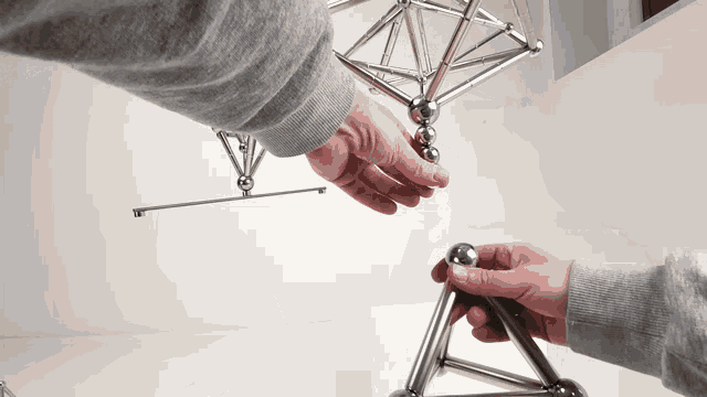 a person in a grey sweatshirt is playing with a magnetic toy