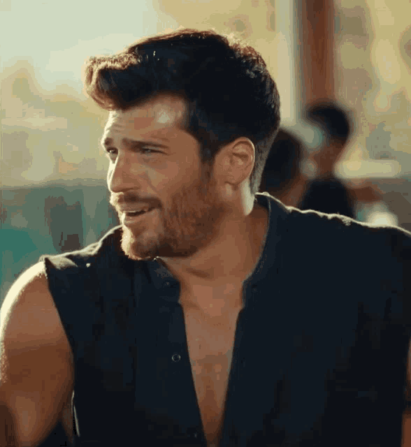 a man with a beard is wearing a black shirt without sleeves