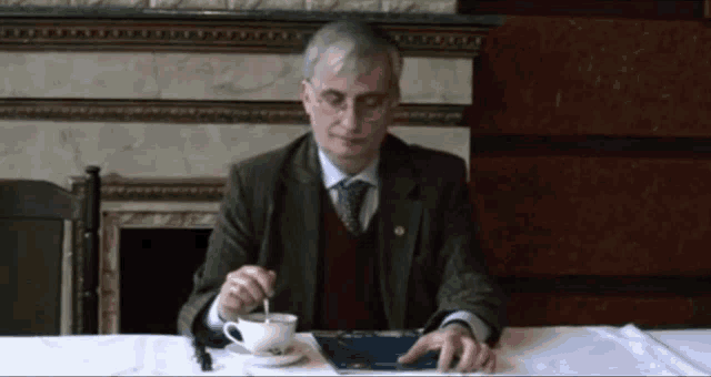 a man is sitting at a table with a cup of coffee