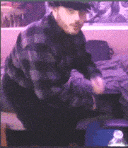 a man in a plaid shirt and hat is kneeling on a bed