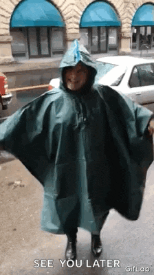 a woman wearing a green poncho with a hood says see you later