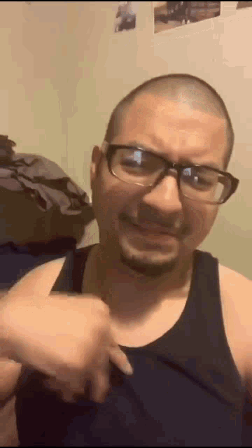 a bald man wearing glasses and a black tank top