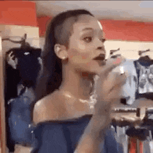 a woman with a shaved head is standing in a clothing store and talking to someone .