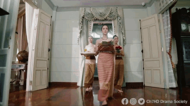 a woman in a striped dress is standing in a room with other women and the words ch7hd drama society on the bottom