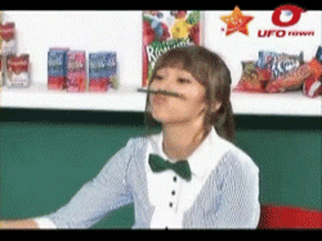 a woman wearing a bow tie holds a pencil in her mouth in front of a ufo logo