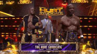 two wrestlers standing on a stage with a sign that says the hurt syndicate