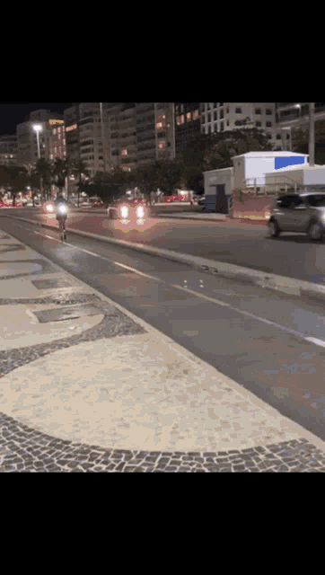 a person on a motorcycle is riding down a street at night
