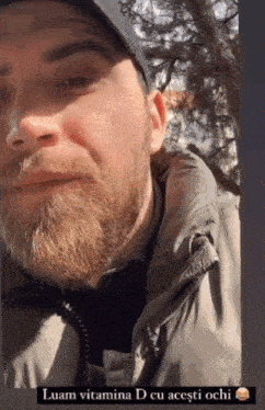 a man with a beard is wearing a hat and a jacket with the words luam vitamina d cu acesti ochi below him