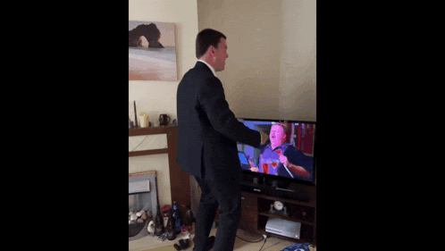 a man in a suit is standing in front of a television