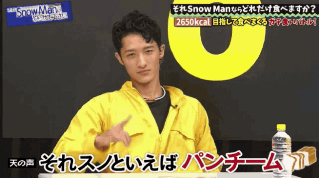 a man in a yellow jacket is pointing at something in front of a sign that says snowman