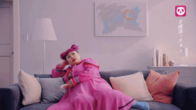 a woman in a pink dress is sitting on a couch with pillows