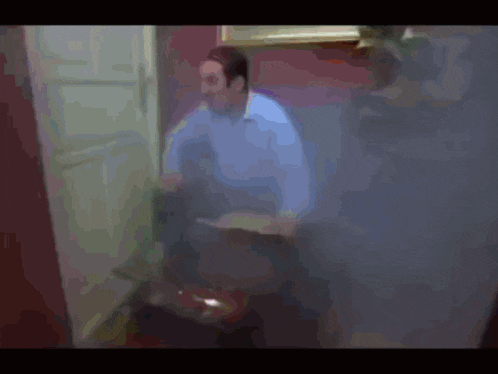 a man in a blue shirt is standing in a room
