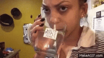 a woman drinking a glass of water with a sticker on it that says white people tears .