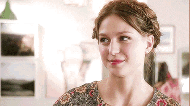 a woman wearing a braided hairstyle and earrings is smiling