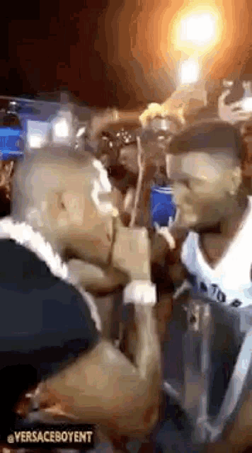 a man is kissing another man on the cheek in a crowd of people .