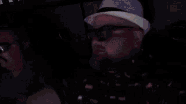 a man wearing a hat and sunglasses is watching a movie in a theater .