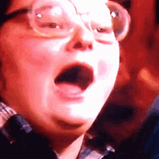 a close up of a person 's face with their mouth open and glasses on .