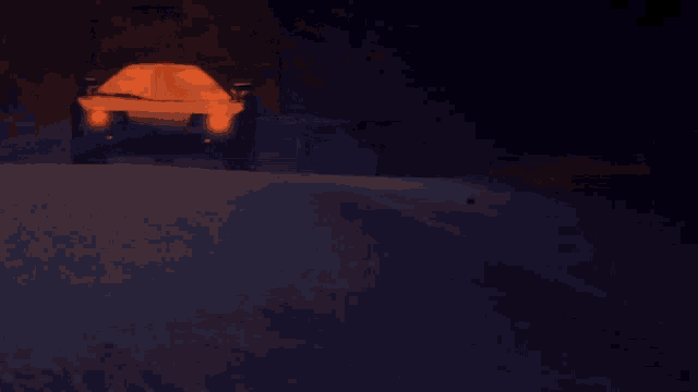 a car is driving down a road at night with the headlights on