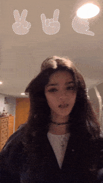 a girl with long dark hair is wearing a choker and a peace sign