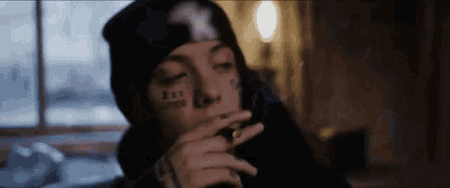 a person with tattoos on their face is smoking a cigarette