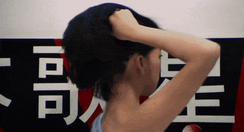 a woman adjusts her hair in front of a sign that says ' a ' on it