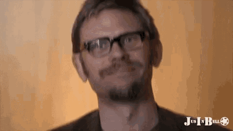 a man with glasses and a beard is smiling and looking at the camera .