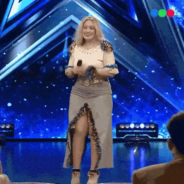 a woman stands on a stage holding a microphone