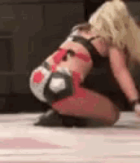a woman in a wrestling outfit is kneeling down on a wrestling mat .