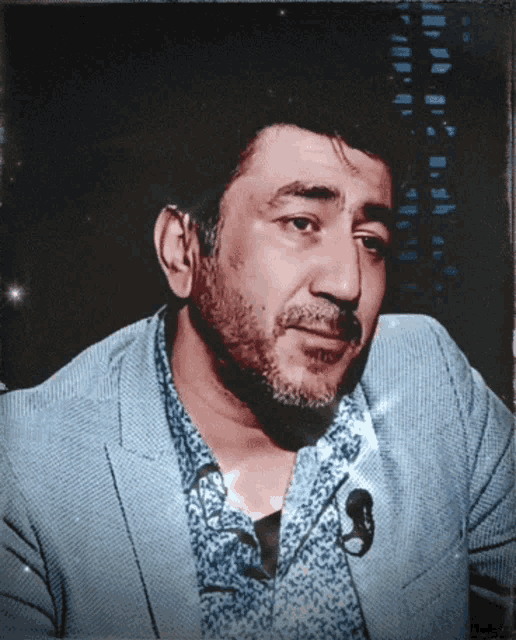 a man with a beard wearing a blue jacket and a blue shirt