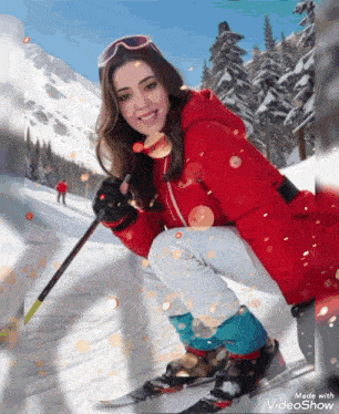 a woman in a red jacket is skiing down a snowy slope