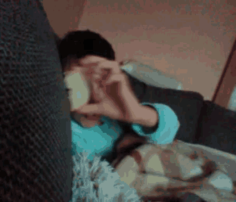 a person is sitting on a couch making a heart shape with their hands .
