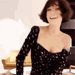 a woman in a black floral dress is smiling