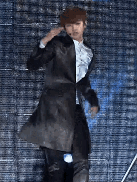 a man in a black coat and white shirt is dancing