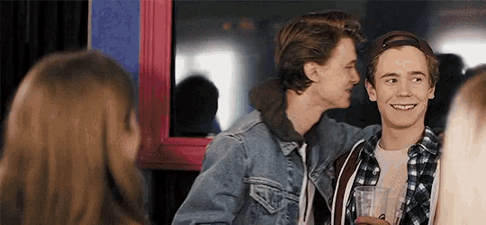 a group of young men are standing next to each other in a room and talking to each other .
