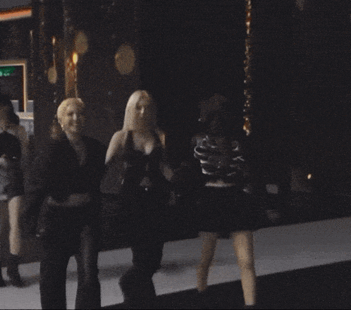 three women are walking down a runway holding hands and smiling