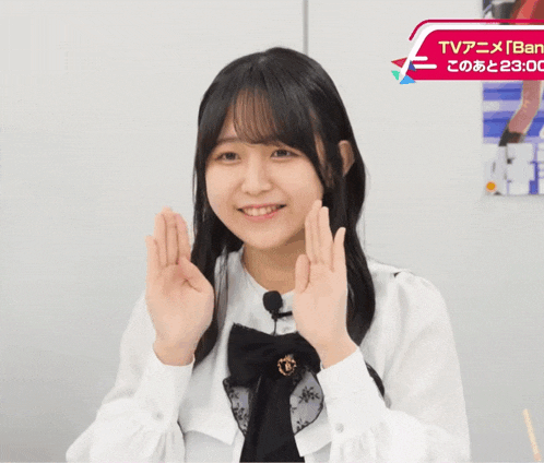 a girl making a peace sign in front of a sign that says tv