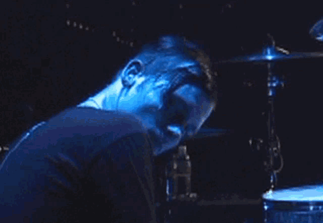 a man in a blue shirt is playing a drum set