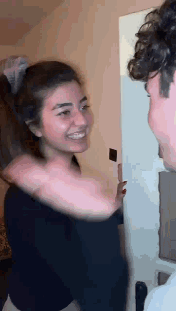a man and a woman are standing next to each other in a room and the woman is smiling .