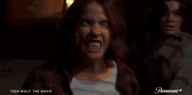 a woman with blue eyes is making a funny face while a man looks on .